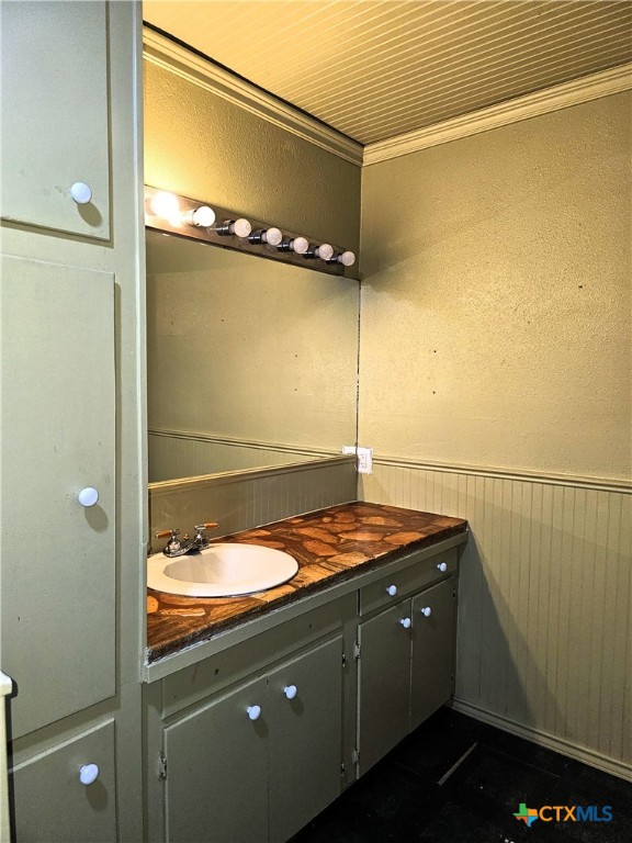 bathroom featuring ornamental molding, vanity, and wooden walls