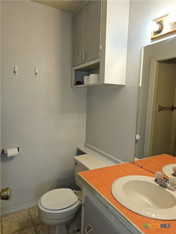 bathroom featuring tile patterned flooring, vanity, a textured ceiling, and toilet