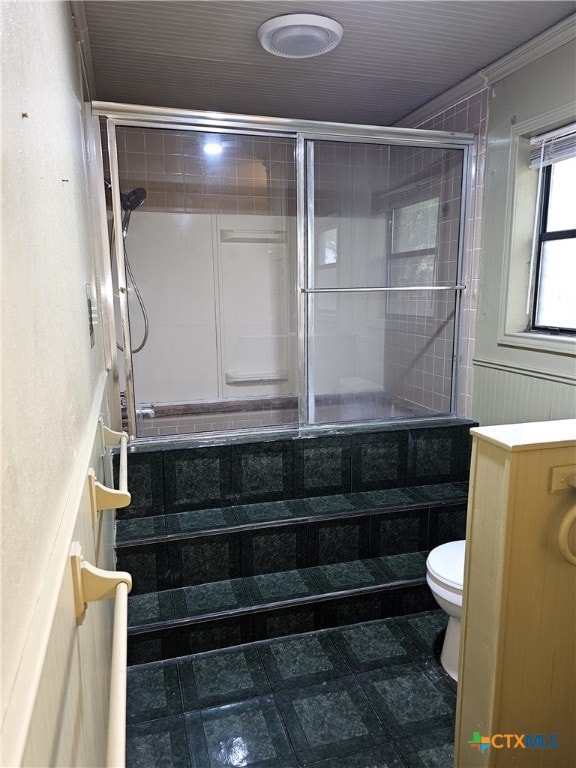 bathroom with tiled shower, toilet, and ornamental molding