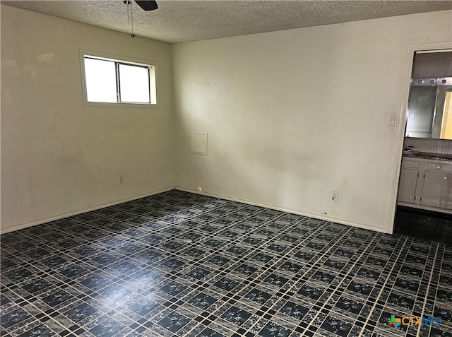 empty room featuring ceiling fan and a textured ceiling