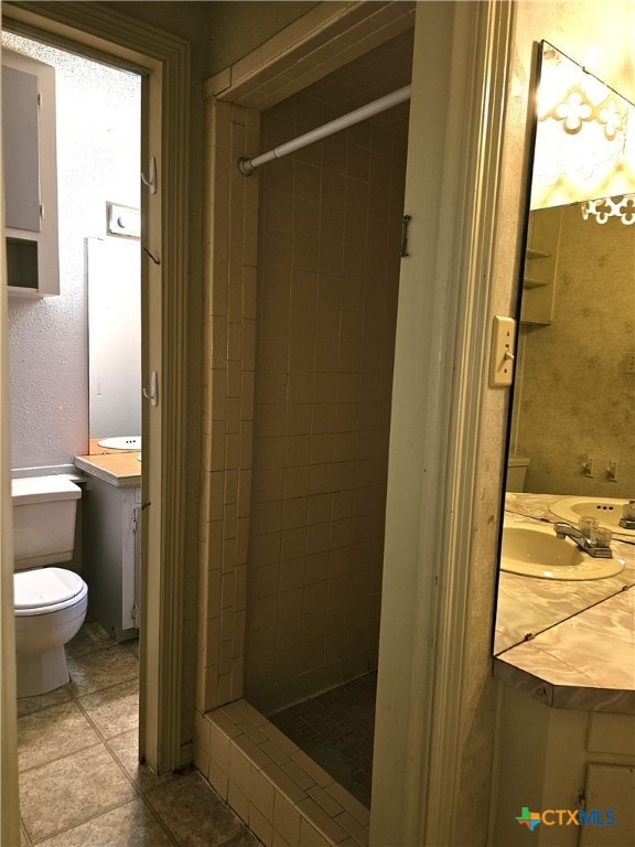 bathroom featuring tiled shower, tile patterned floors, vanity, and toilet