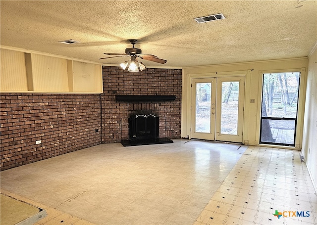 unfurnished living room featuring ceiling fan, a brick fireplace, brick wall, crown molding, and a textured ceiling