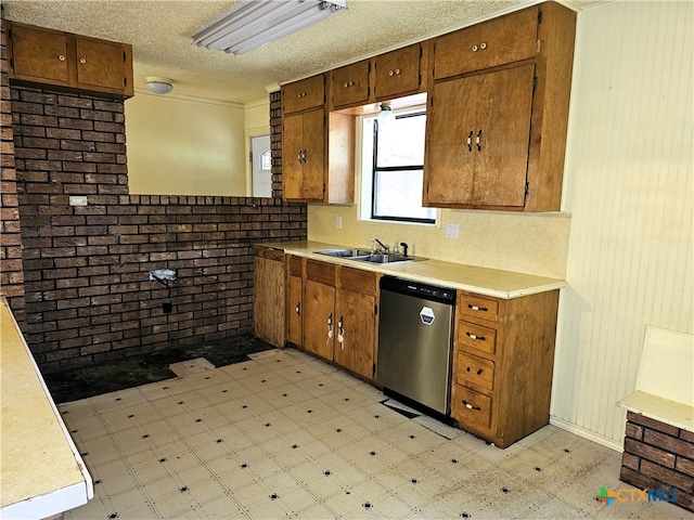 kitchen featuring brick wall, a textured ceiling, stainless steel dishwasher, and sink