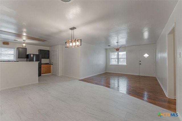 unfurnished living room featuring a chandelier