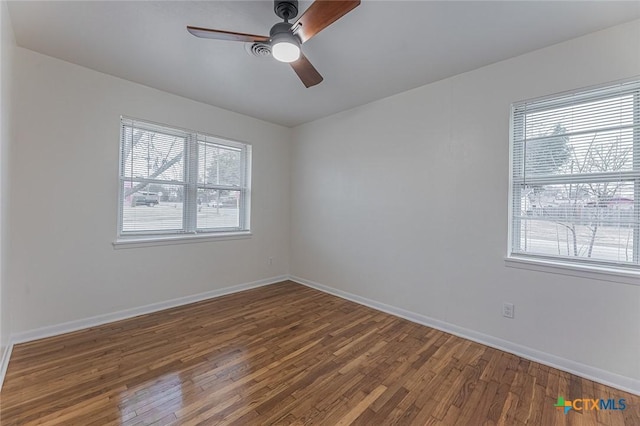 empty room with dark wood-type flooring, ceiling fan, and a healthy amount of sunlight