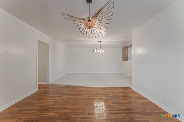 unfurnished room with wood-type flooring and a chandelier