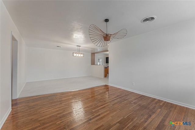 empty room featuring hardwood / wood-style floors and an inviting chandelier