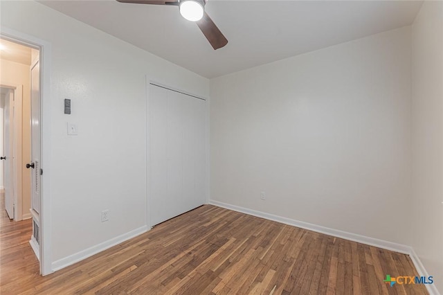 unfurnished bedroom with hardwood / wood-style flooring, ceiling fan, and a closet