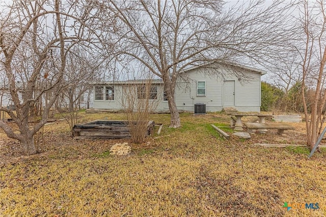 rear view of property featuring central AC unit and a yard