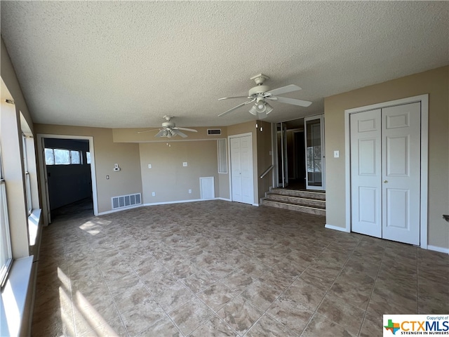 unfurnished living room featuring ceiling fan and a textured ceiling