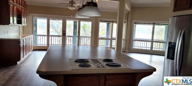 kitchen with crown molding, stainless steel refrigerator with ice dispenser, ceiling fan, a textured ceiling, and electric stovetop