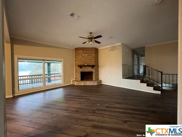 unfurnished living room with dark wood-type flooring, crown molding, ceiling fan, a textured ceiling, and a fireplace