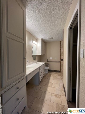 bathroom featuring tile patterned flooring, vanity, toilet, and a textured ceiling