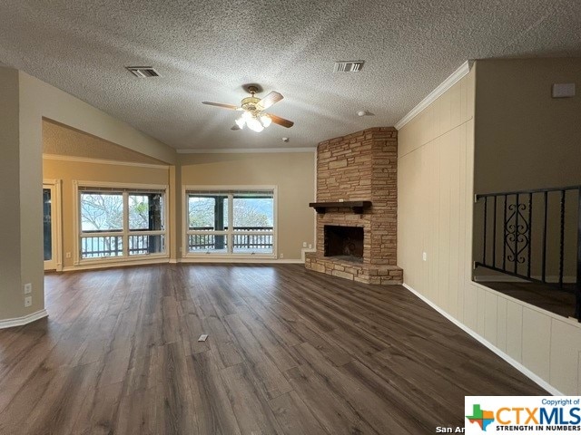 unfurnished living room featuring ceiling fan, dark hardwood / wood-style flooring, crown molding, a textured ceiling, and a fireplace