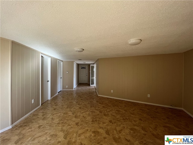 unfurnished room featuring wooden walls and a textured ceiling