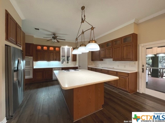 kitchen featuring decorative light fixtures, a kitchen island, crown molding, and appliances with stainless steel finishes