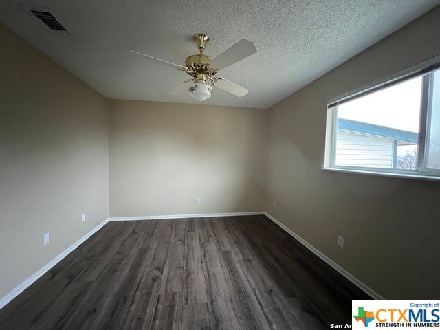 spare room featuring a textured ceiling, ceiling fan, and dark wood-type flooring