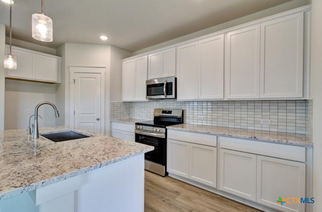 3625 Meteor Rd, New Braunfels, TX 78130 - kitchen with stainless steel appliances, a sink, white cabinets, light wood-style flooring, and recessed lighting