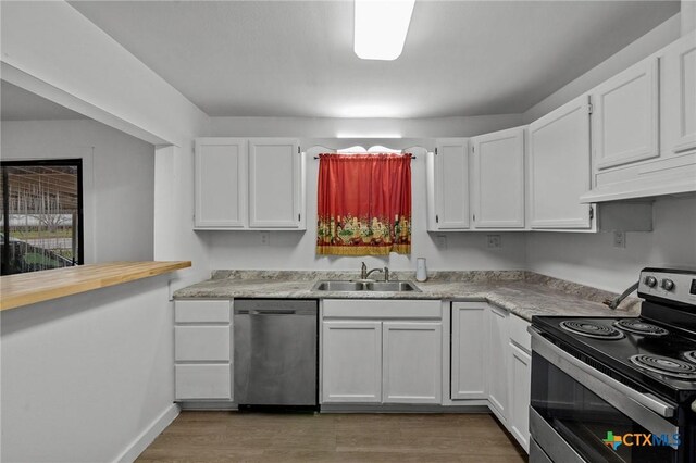 409 E Empresario St, Refugio, TX 78377 - kitchen with dark wood-style floors, appliances with stainless steel finishes, light countertops, white cabinetry, and a sink