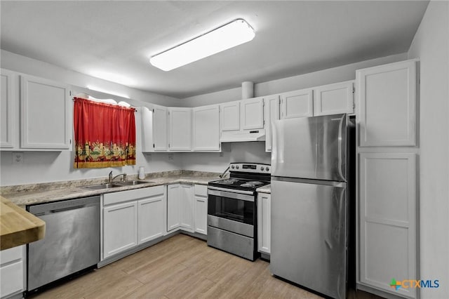 409 E Empresario St, Refugio, TX 78377 - kitchen with white cabinets, stainless steel appliances, light countertops, under cabinet range hood, and a sink