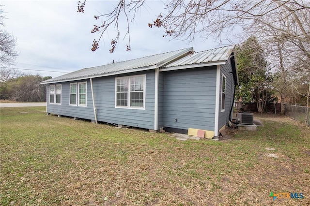 409 E Empresario St, Refugio, TX 78377 - view of side of property with central AC, metal roof, and a lawn