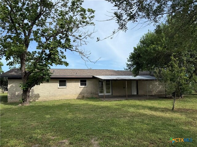 706 Edinburgh St, Victoria, TX 77904 - rear view of house featuring french doors, a yard, a carport, and brick siding