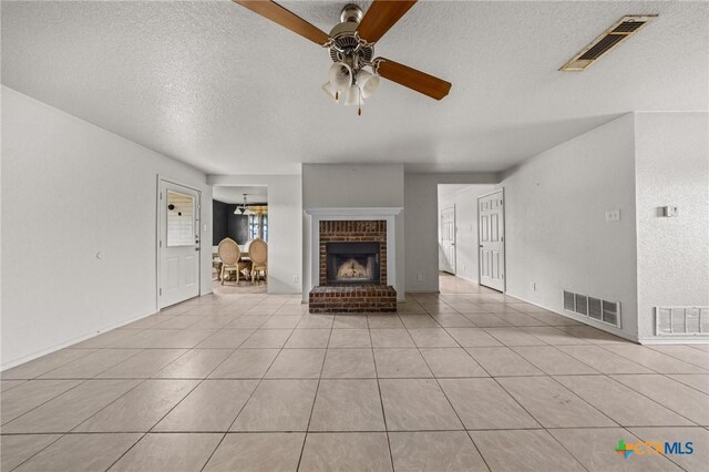 3810 John Haedge Dr, Killeen, TX 76549 - unfurnished living room featuring a textured ceiling, ceiling fan, a brick fireplace, and light tile patterned flooring