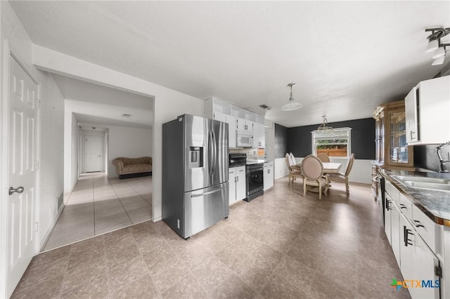 3810 John Haedge Dr, Killeen, TX 76549 - kitchen with appliances with stainless steel finishes, white cabinetry, dark countertops, and hanging light fixtures