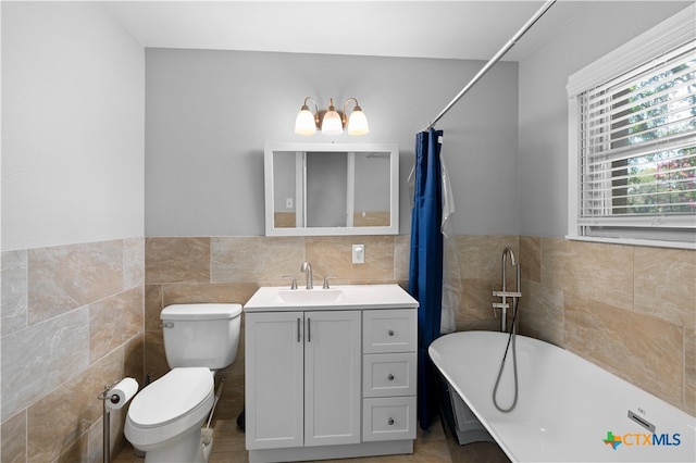 bathroom with tile walls, a bathtub, vanity, and toilet