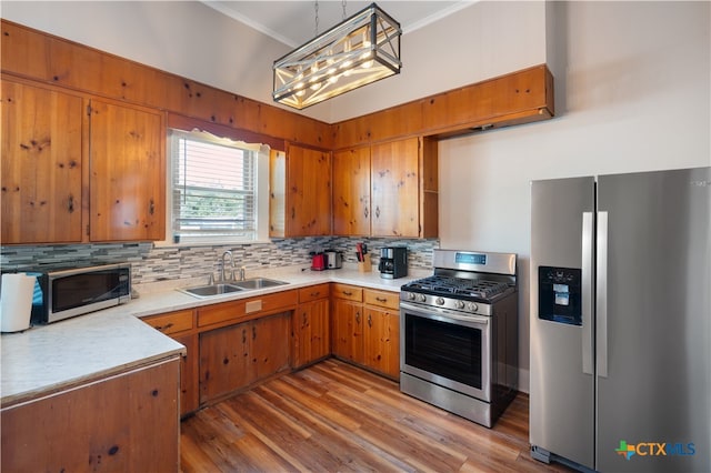 kitchen featuring sink, appliances with stainless steel finishes, decorative light fixtures, backsplash, and light wood-type flooring