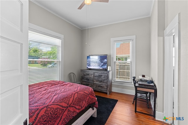 bedroom with multiple windows, hardwood / wood-style floors, ceiling fan, and crown molding