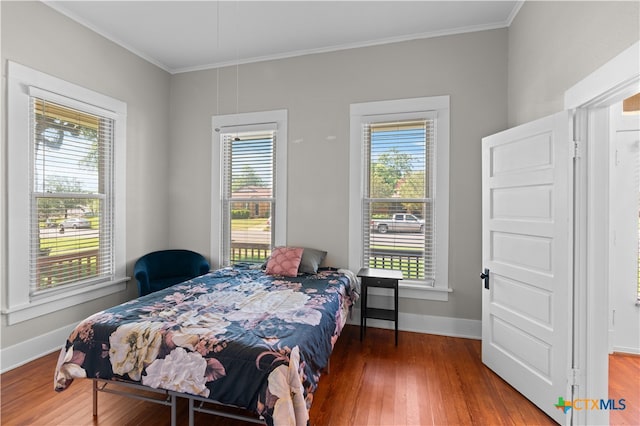 bedroom featuring multiple windows, hardwood / wood-style floors, and crown molding