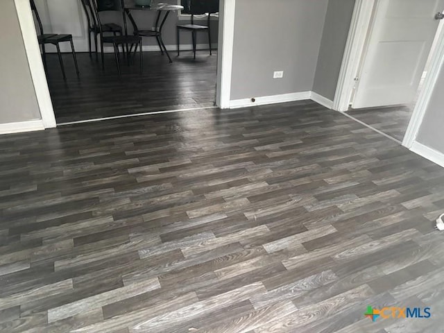 unfurnished dining area featuring wood finished floors and baseboards