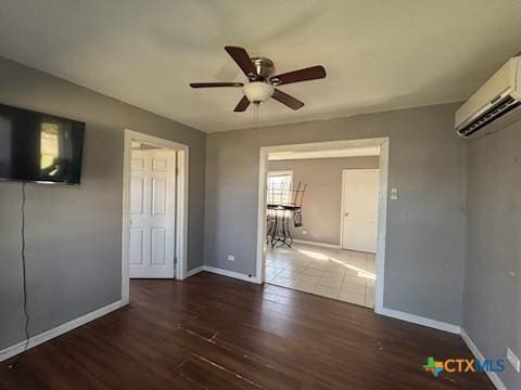 unfurnished bedroom featuring baseboards, wood finished floors, an AC wall unit, and ceiling fan