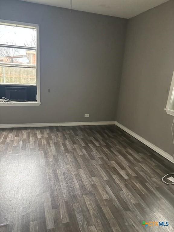 unfurnished room featuring baseboards and dark wood-style flooring