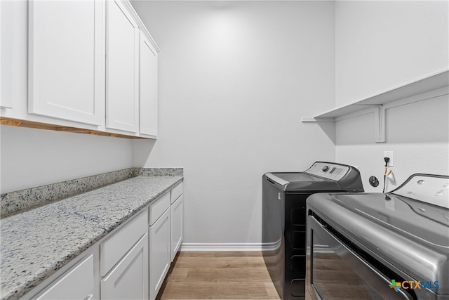 clothes washing area with cabinets, light wood-type flooring, and independent washer and dryer