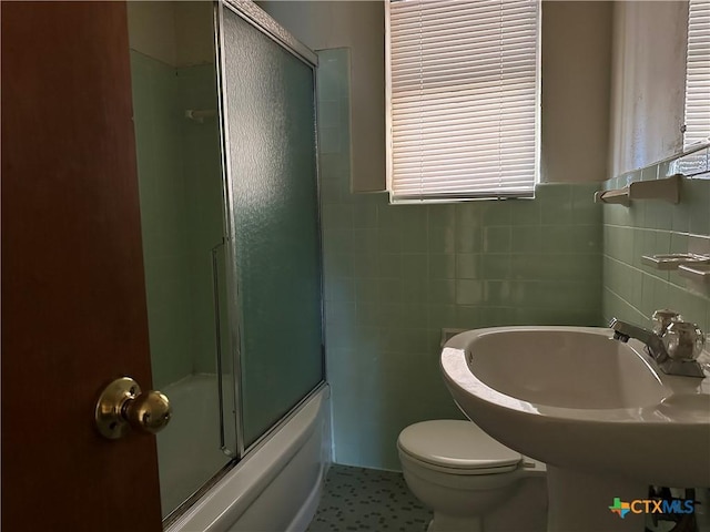 full bathroom featuring tile patterned flooring, toilet, enclosed tub / shower combo, tile walls, and sink