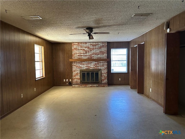 unfurnished living room featuring ceiling fan, wooden walls, and a fireplace