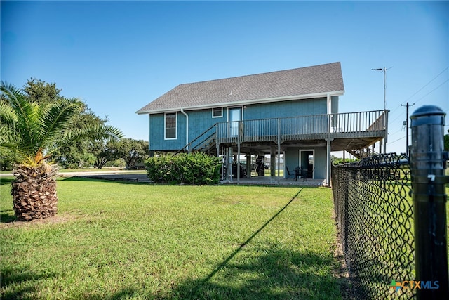 rear view of property featuring a wooden deck and a lawn