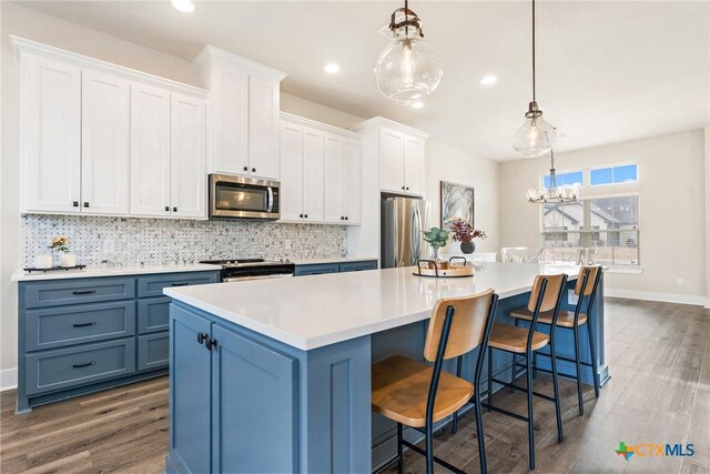 837 Gallant Fox Rd, Hewitt, TX 76643 - kitchen with appliances with stainless steel finishes, dark wood-style floors, a large island, decorative backsplash, and light countertops
