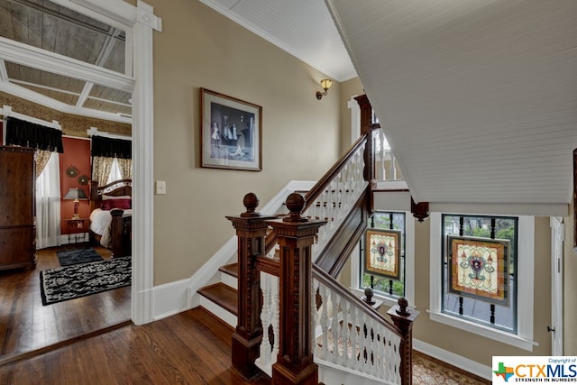 stairs featuring hardwood / wood-style floors, vaulted ceiling, and ornamental molding