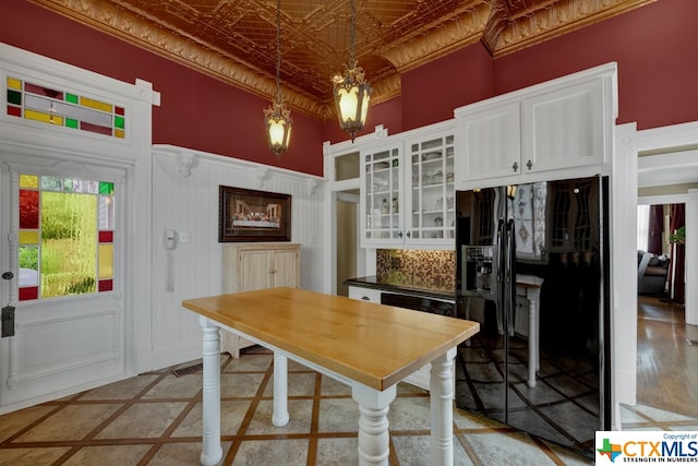 kitchen with black appliances, tasteful backsplash, white cabinetry, hanging light fixtures, and light hardwood / wood-style floors