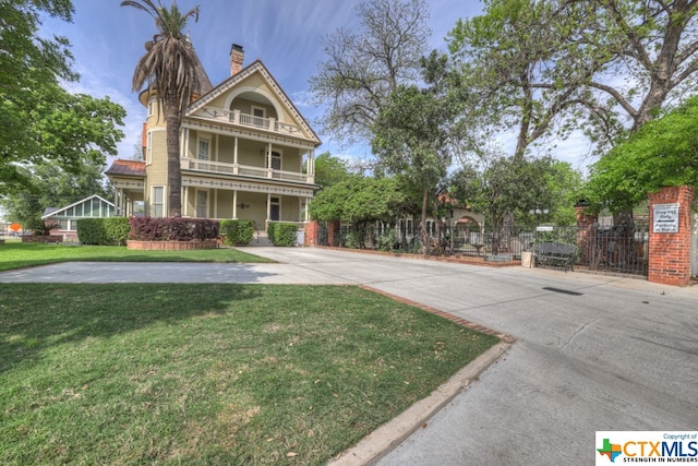 victorian home featuring a front lawn and a balcony