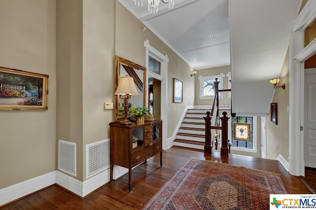 foyer with ornamental molding, dark hardwood / wood-style floors, and a chandelier