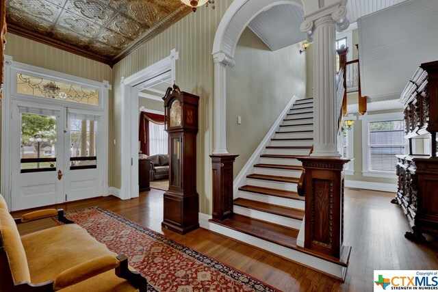 entrance foyer featuring french doors, dark hardwood / wood-style flooring, crown molding, and decorative columns