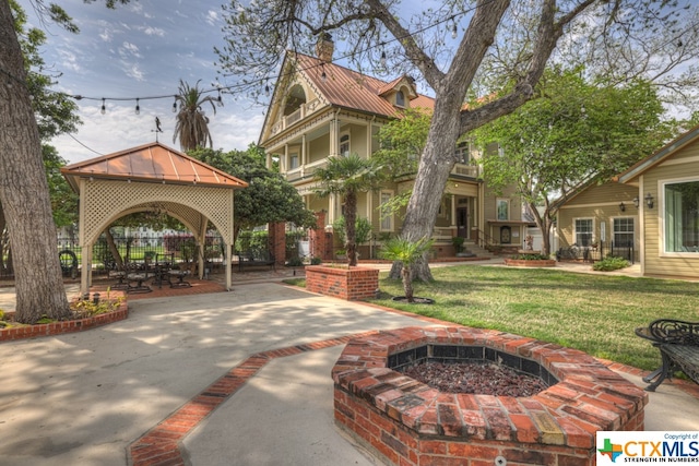 view of property's community featuring a patio area, a yard, a fire pit, and a gazebo