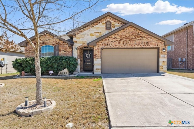 view of front of property with an attached garage, concrete driveway, a front lawn, stone siding, and brick siding