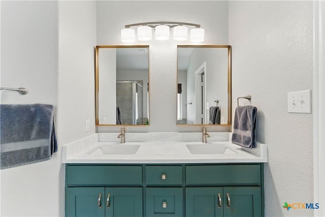 bathroom featuring double vanity, a stall shower, and a sink