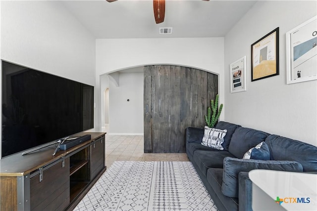 living room featuring arched walkways, visible vents, a ceiling fan, and light tile patterned floors