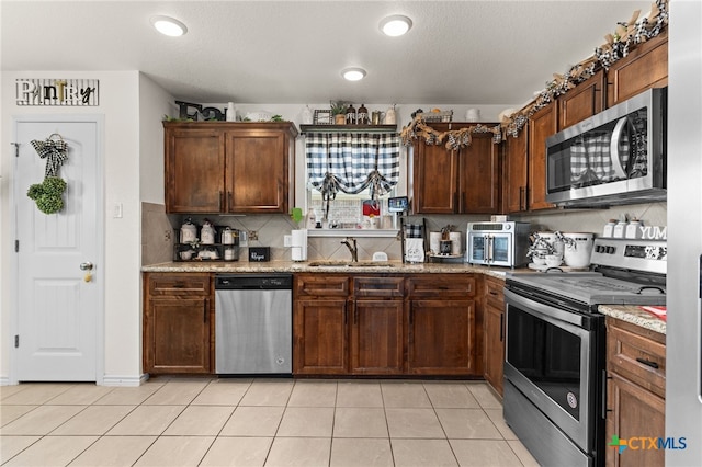 1037 Declaration Dr, Copperas Cove, TX 76522 - kitchen featuring appliances with stainless steel finishes, a sink, light tile patterned floors, and backsplash